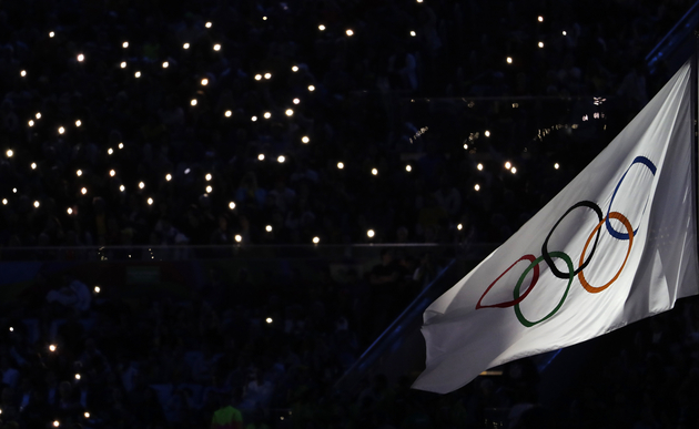 Smartphone lights illuminate the Olympic flag at the start of the closing ceremony [AP Photo/Natacha Pisarenko]
